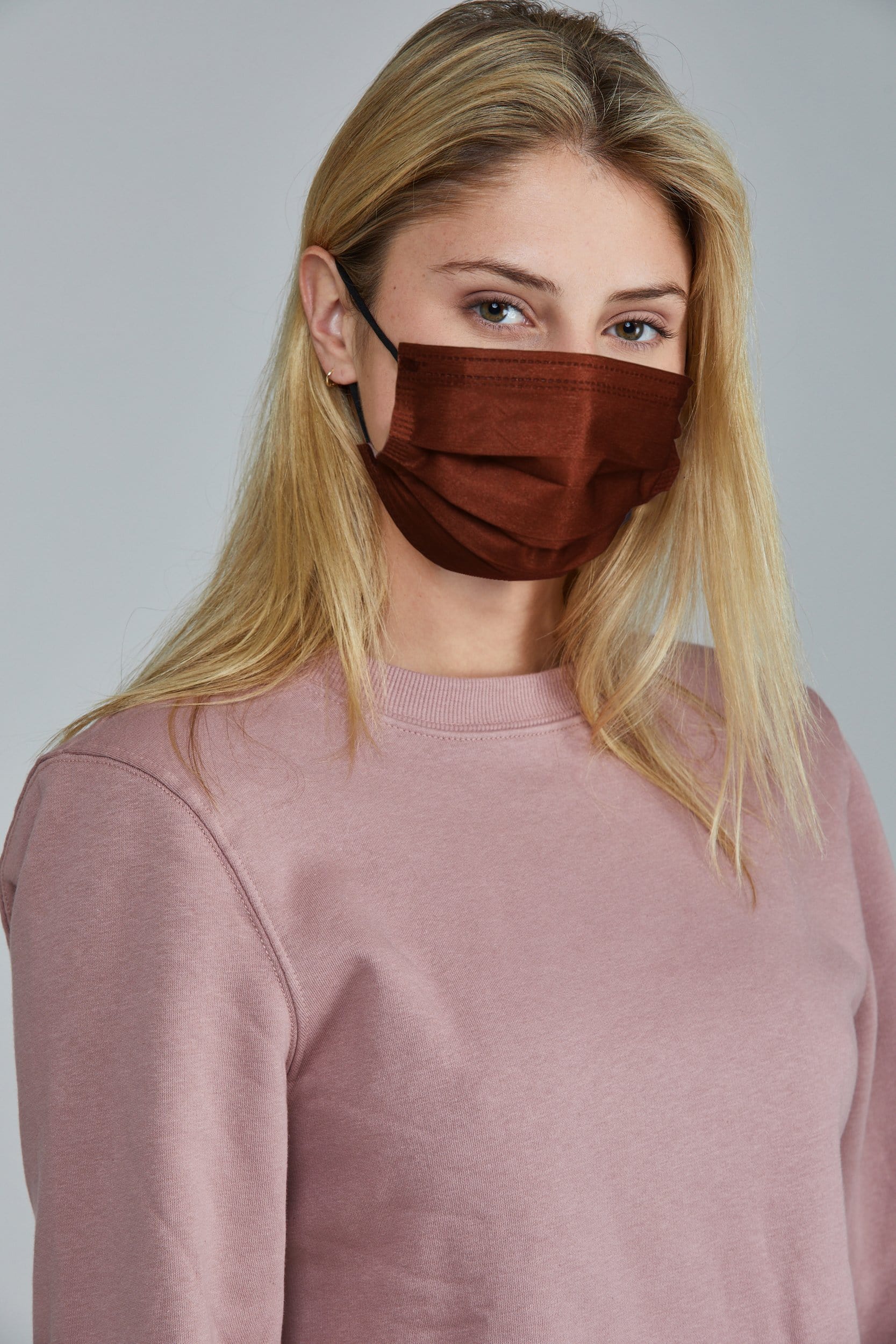 Woman wearing stylish Rust Pleated face mask, with three layers & high quality breathable fabric.