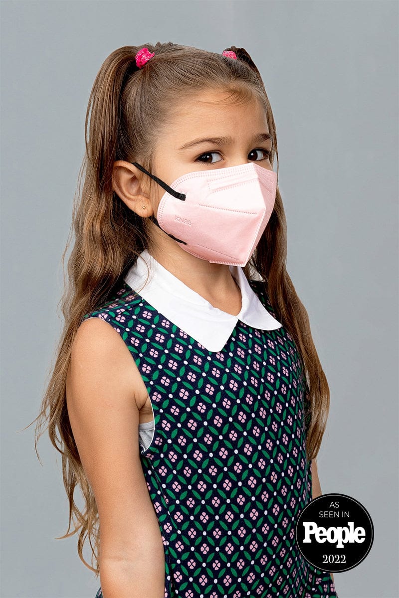 Child wearing stylish kid sized Light Pink KN95 face mask, with high quality breathable fabric.