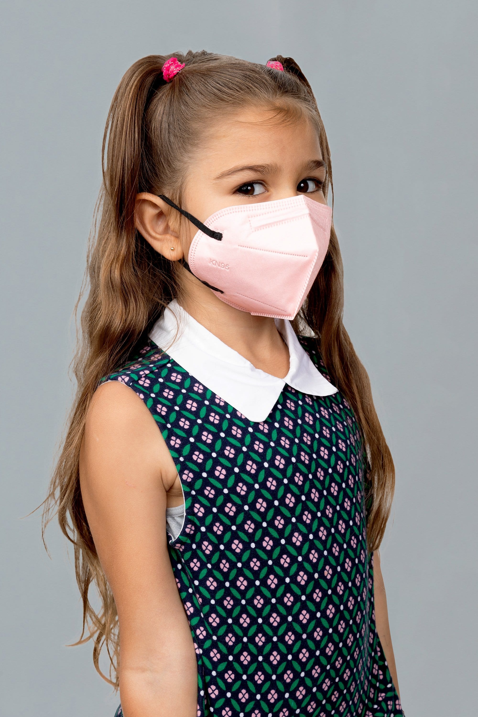 Child wearing stylish kid sized Light Pink KN95 face mask, with high quality breathable fabric.
