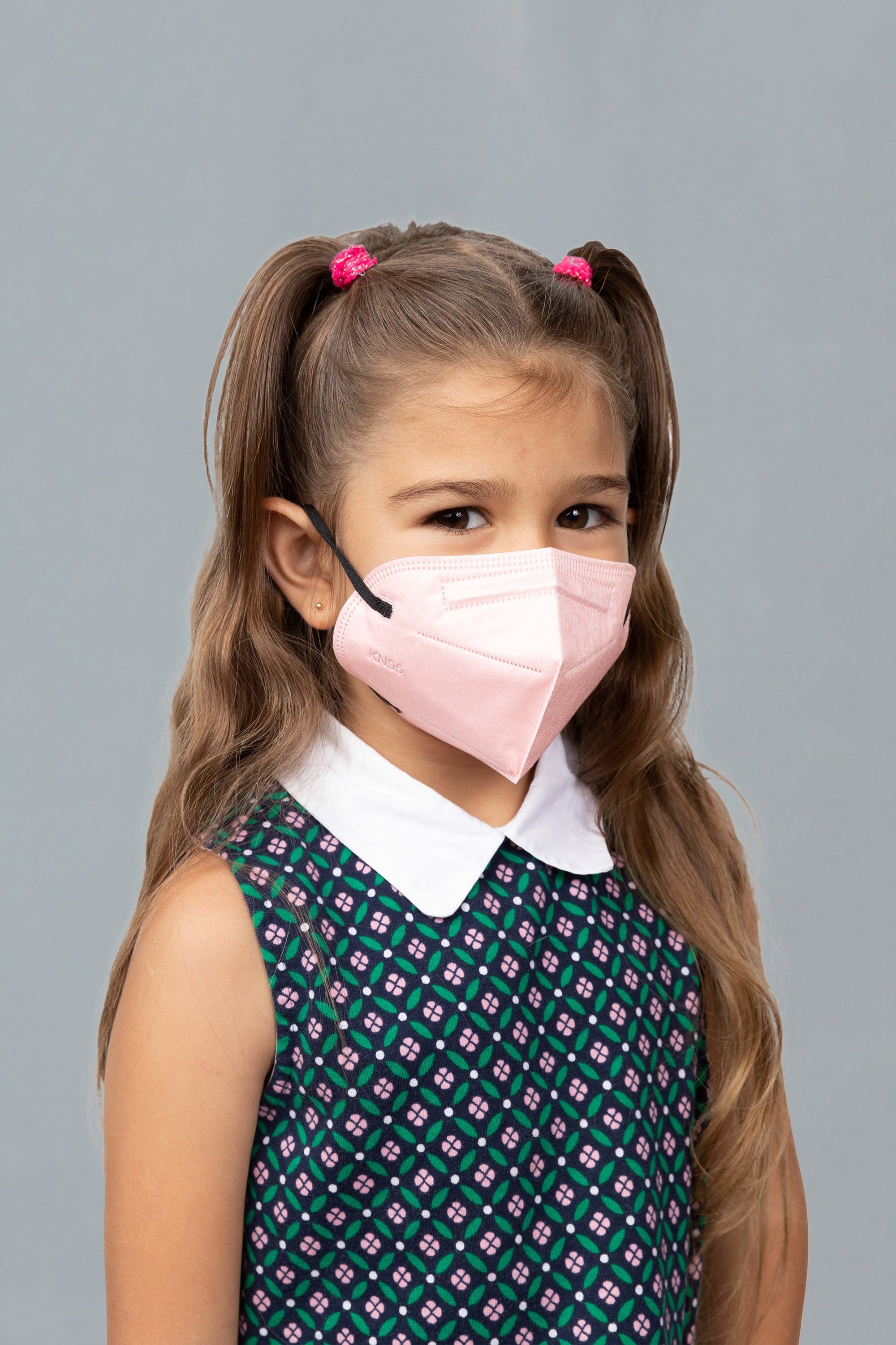 Child wearing stylish kid sized Light Pink KN95 face mask, with high quality breathable fabric.