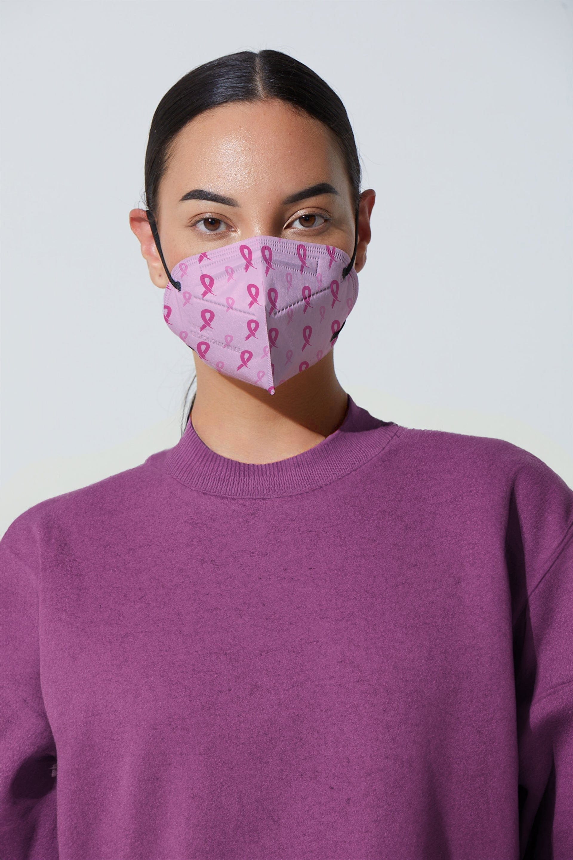 Woman wearing stylish pink breast cancer awareness ribbon printed KN95 face mask, with high quality breathable fabric. 